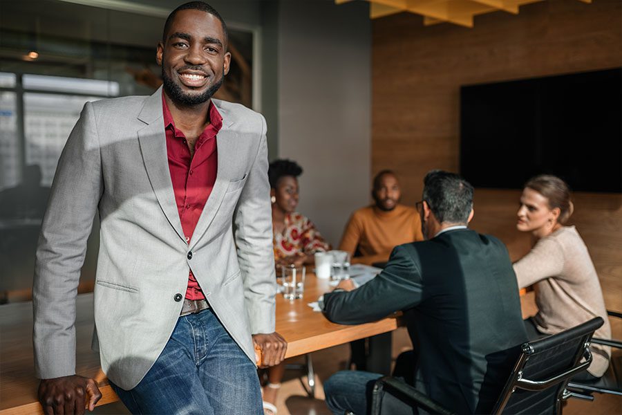Business Insurance - Portrait of a Black Business Man During a Meeting with Co Workers